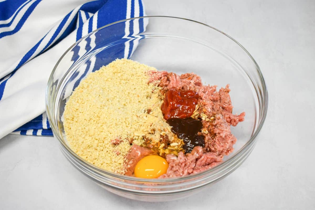 1- Glass bowl with ground turkey, panko breadcrumbs, egg, ketchup, steak sauce, onion soup mix, and seasonings before mixing.