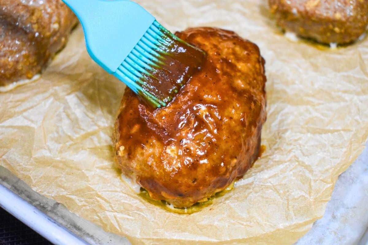 4- Brushing glaze onto a partially baked mini turkey meatloaf with a blue silicone brush.